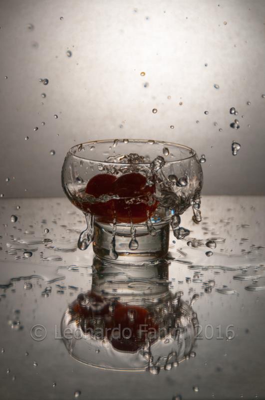 two tomatoes splashed in a glass of water